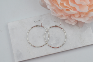 Sterling silver drop round hoop earrings pictured from above on a white marble slab. 