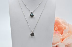 Two separate sterling silver labradorite necklaces pictured on a jewelry stand showing varying chain lengths.