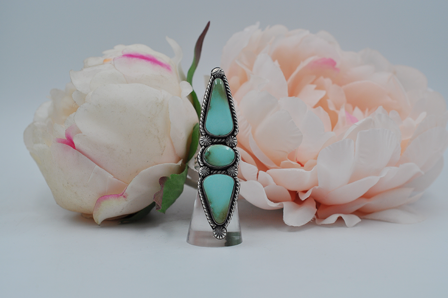 This large Royston turquoise ring features stones stones; one oval and two elongated teardrop shapes surrounded by sterling silver twisted rope and starburst ball embellishments in a satin finish. This statement ring is pictured here on a model. US Size 7.5