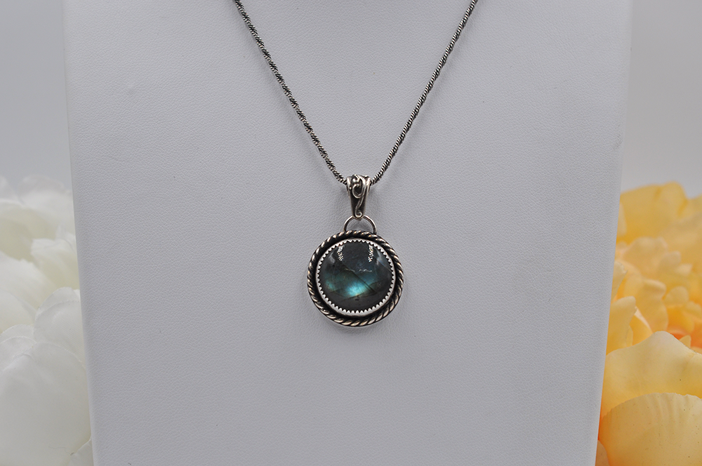 Silver necklace with a greenish-blue labradorite pendant on a white background