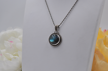 Silver necklace with a greenish-blue stone pendant on a white background