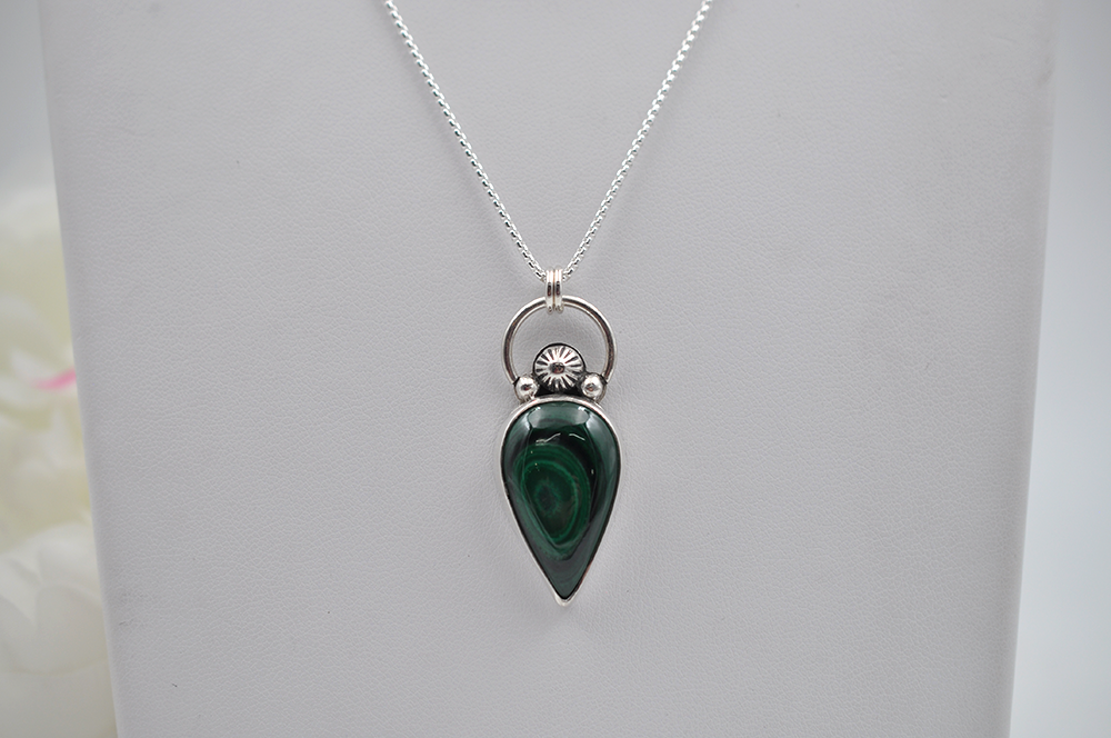Necklace with a green teardrop pendant on a white background