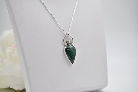 Green teardrop pendant on a silver chain against a white background