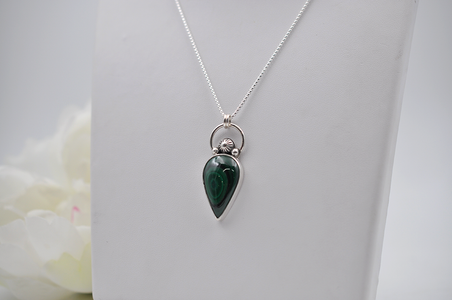 Teardrop-shaped green pendant on a silver chain against a white background