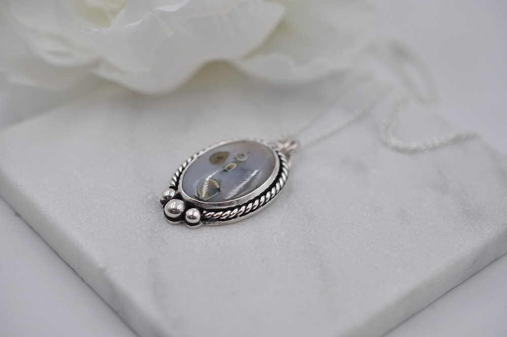 Silver pendant with floral design on a white surface