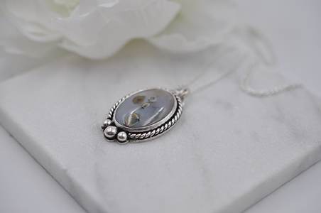 Silver pendant with floral design on a white surface