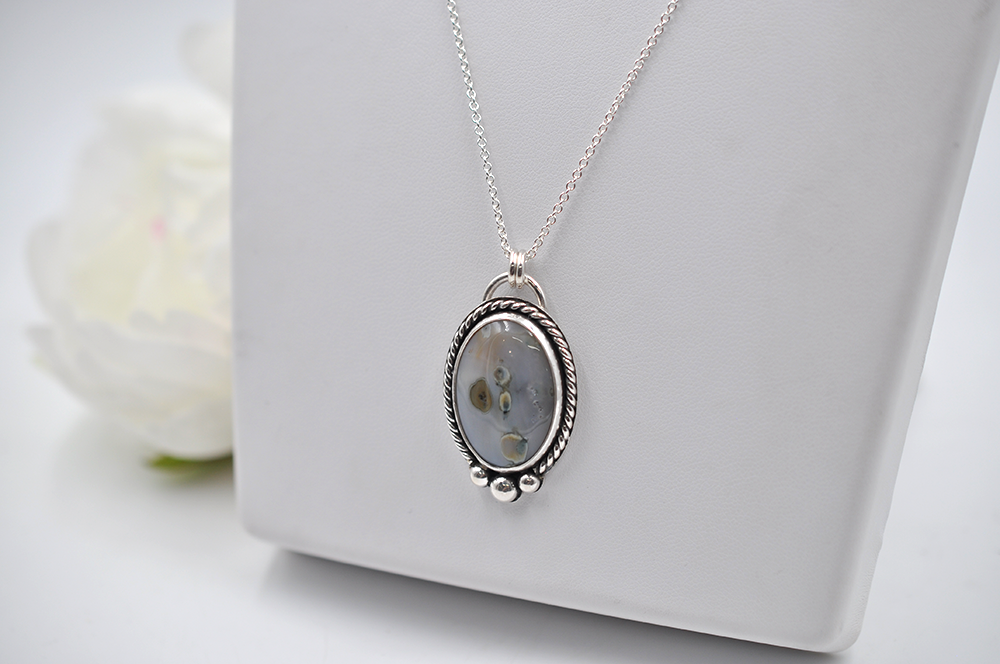 Silver necklace with a pendant on a white surface