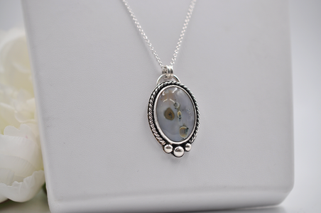 Silver necklace with a pendant on a white surface