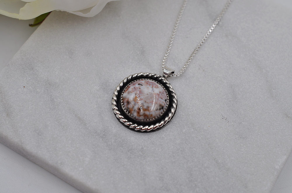 Necklace with a round pendant on a gray surface