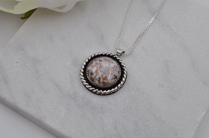 Necklace with a round pendant on a gray surface