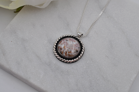 Necklace with a round pendant on a gray surface