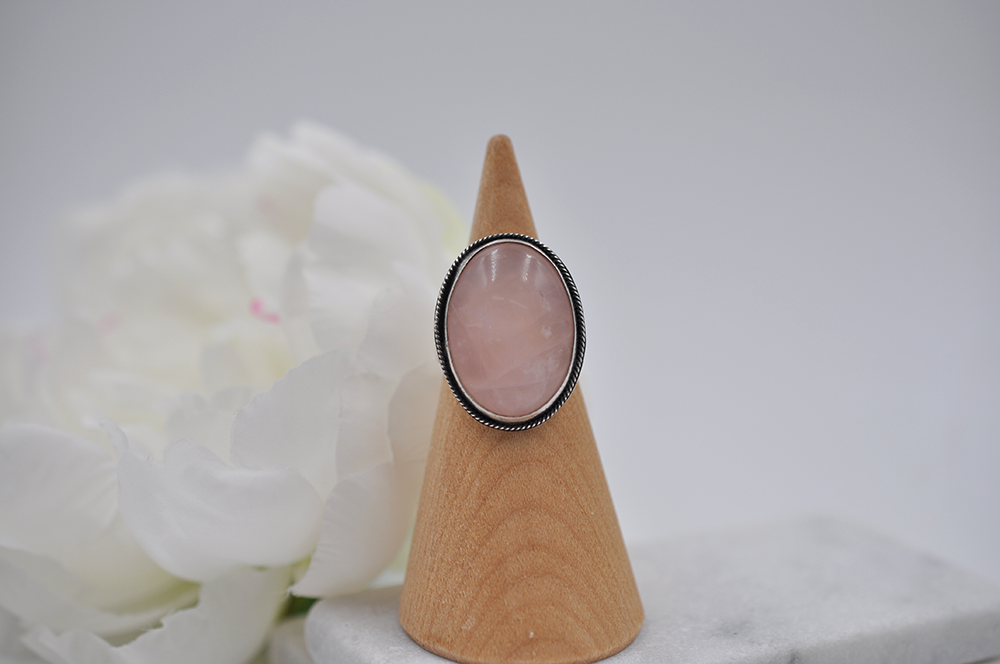 Ring with a pink stone on a wooden cone against a white background