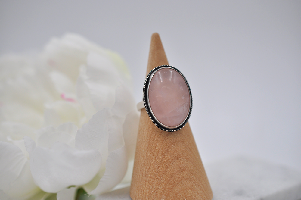 Ring with pink stone on a wooden stand against a white background