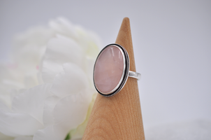 Ring with pink stone on a wooden stand against a white background