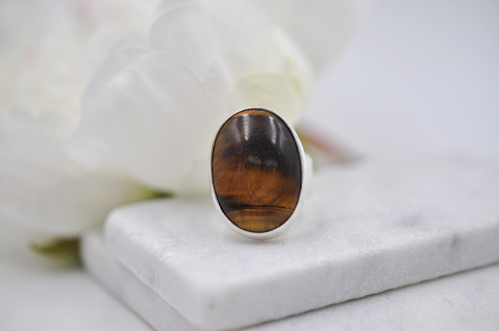 Ring with a brown tiger's eye stone on a white surface