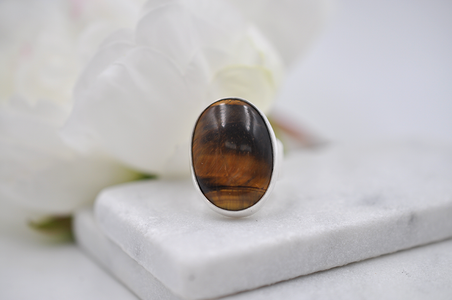 Ring with a brown tiger's eye stone on a white surface