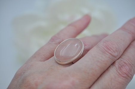 Hand holding a pink stone against a blurred background