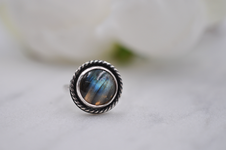 Silver ring with a labradorite stone on a light background