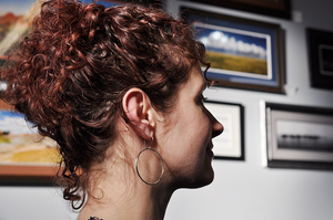 Round sterling silver drop hoop earrings pictured on a model. 