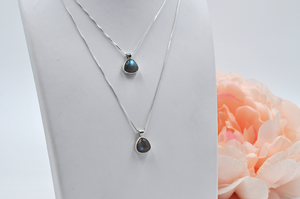 Two separate sterling silver labradorite necklaces pictured on a jewelry stand showing varying chain lengths.