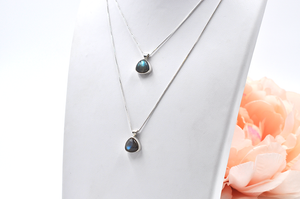 Two separate sterling silver labradorite necklaces pictured on a jewelry stand showing varying chain lengths.