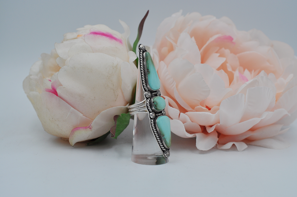 This large Royston turquoise ring features stones stones; one oval and two elongated teardrop shapes surrounded by sterling silver twisted rope and starburst ball embellishments in a satin finish. Picture here is a side view showing the split shank ring band. US Size 7.5