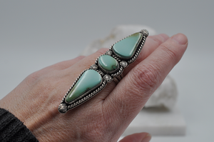 This large Royston turquoise ring features stones stones; one oval and two elongated teardrop shapes surrounded by sterling silver twisted rope and starburst ball embellishments in a satin finish. This statement ring is pictured here on a model. US Size 7.5