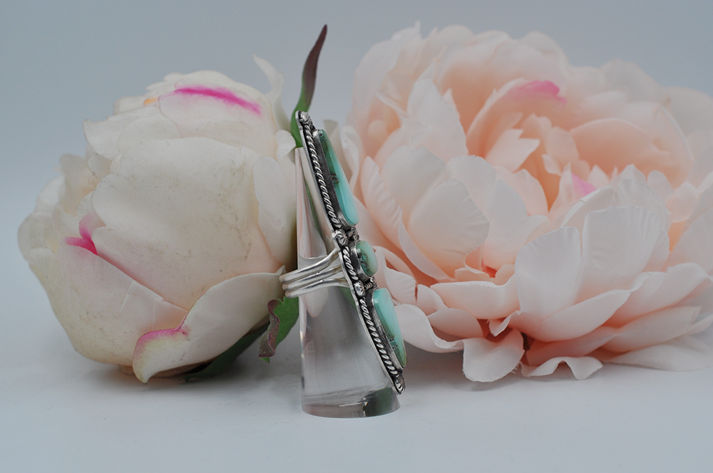 This large Royston turquoise ring features stones stones; one oval and two elongated teardrop shapes surrounded by sterling silver twisted rope and starburst ball embellishments in a satin finish. Picture here is a profile view showing the split shank ring band. US Size 7.5