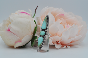 This large Royston turquoise ring features stones stones; one oval and two elongated teardrop shapes surrounded by sterling silver twisted rope and starburst ball embellishments in a satin finish. Picture here is a side view showing the split shank ring band. US Size 7.5